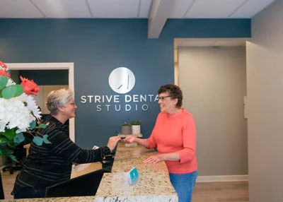 Strive Dental Studio patient talking with our front office coordinator