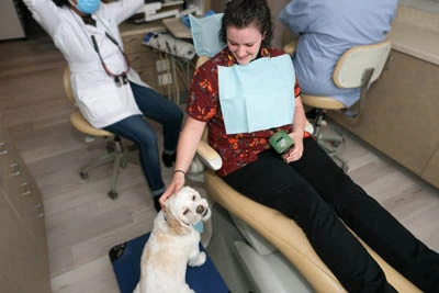 patient petting Dobby the therapy dog during her dental appointment
